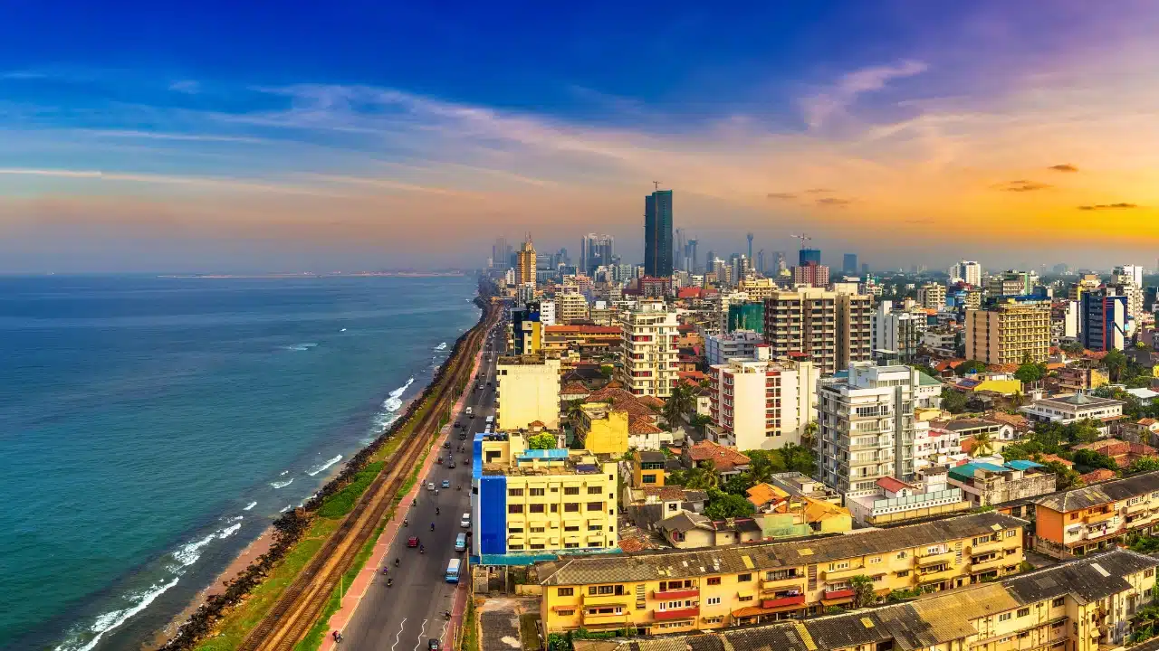 Colombo skyline along the Indian Ocean featuring high-rise buildings, seaside road, and colorful sunset sky in Sri Lanka